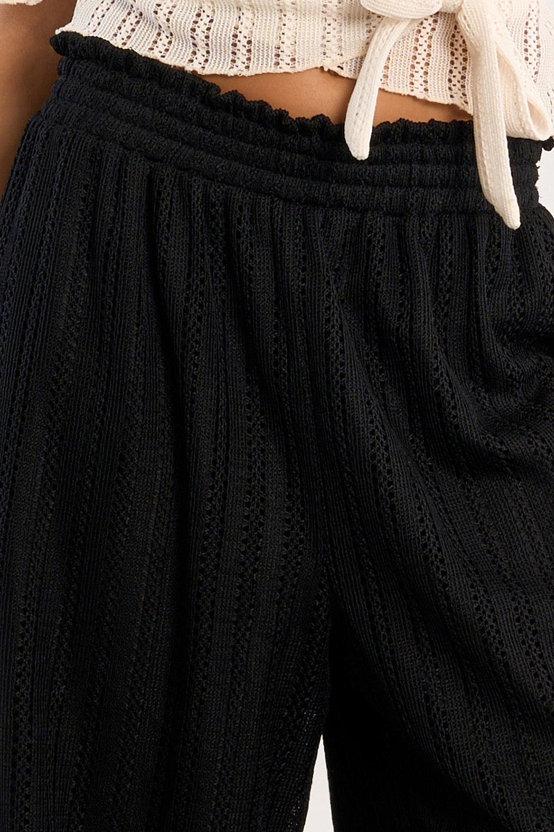 Close up shot of lined black crochet drawstring pants, part of a vacation outfit from a resort wear collection at a Texas boutique.
