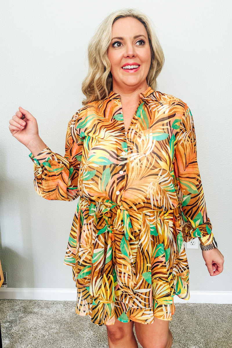 Woman wearing an orange tropical tie-front top and matching skirt, a vacation outfit from a women's boutique.