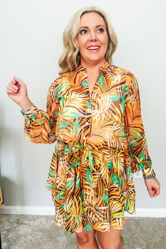 Woman wearing an orange tropical tie-front top and matching skirt, a vacation outfit from a women's boutique.