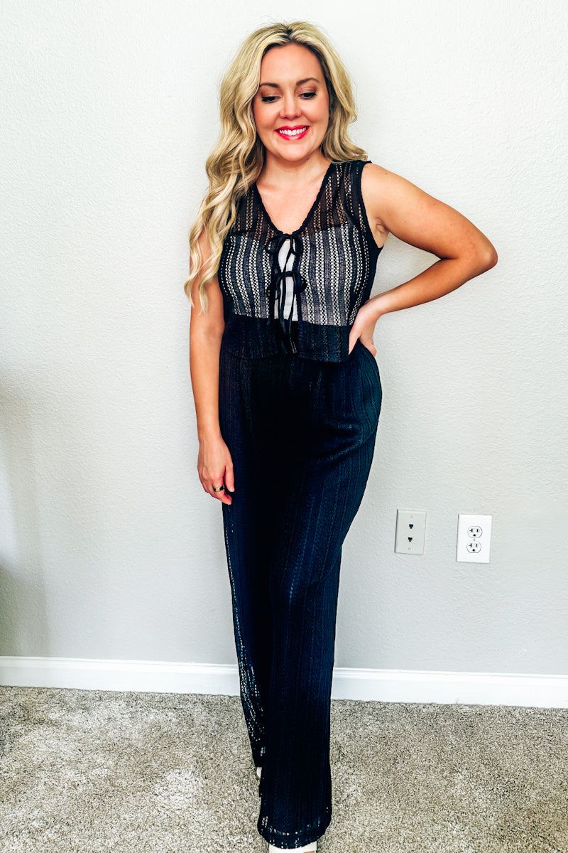 Woman wearing black crochet tie-front resort wear top with coordinated black crochet pants in matching set for women.